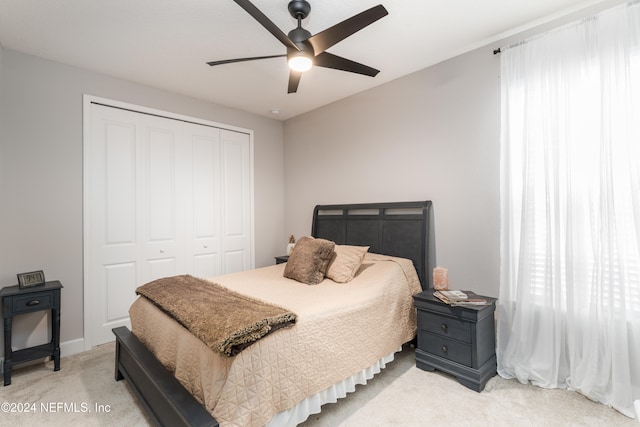 bedroom with ceiling fan, a closet, and light colored carpet