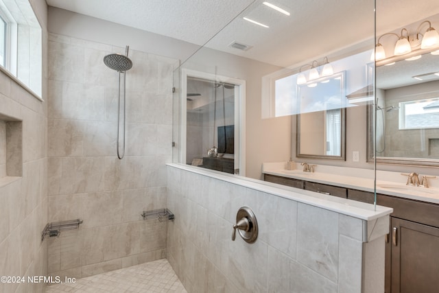 bathroom featuring vanity, a textured ceiling, and a tile shower