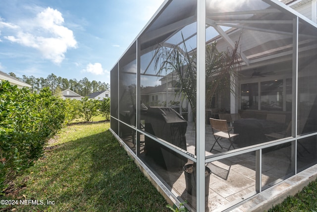 view of property exterior featuring glass enclosure, a yard, and a patio