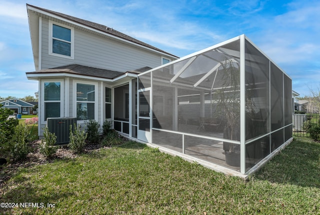 back of property with glass enclosure, cooling unit, and a lawn