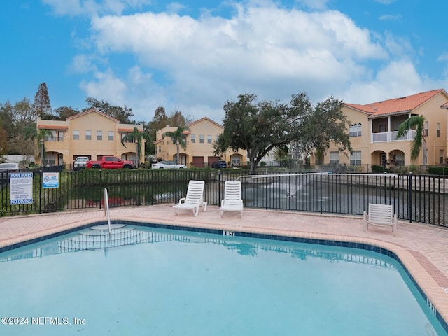 view of swimming pool featuring a water view and a patio area