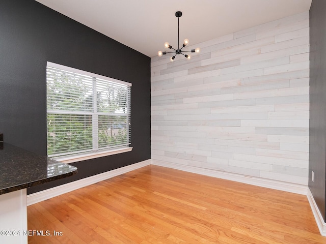 unfurnished dining area with light wood-type flooring and a chandelier