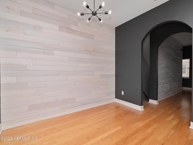 empty room with light hardwood / wood-style flooring and a chandelier