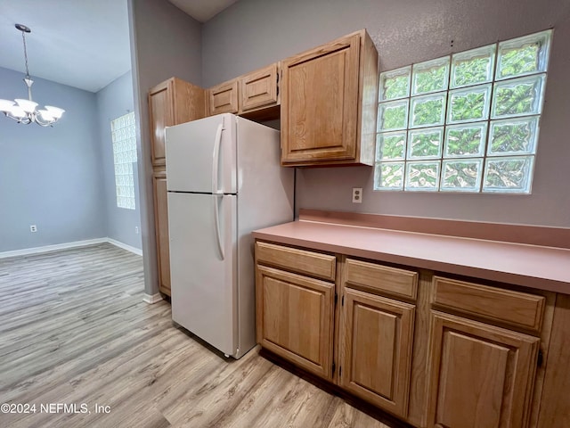 kitchen with light wood-type flooring, an inviting chandelier, white refrigerator, and decorative light fixtures