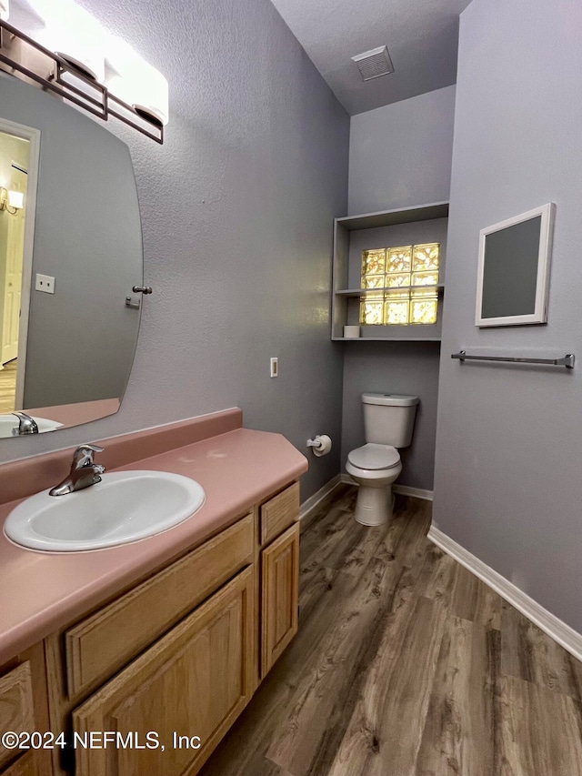 bathroom with wood-type flooring, vanity, and toilet