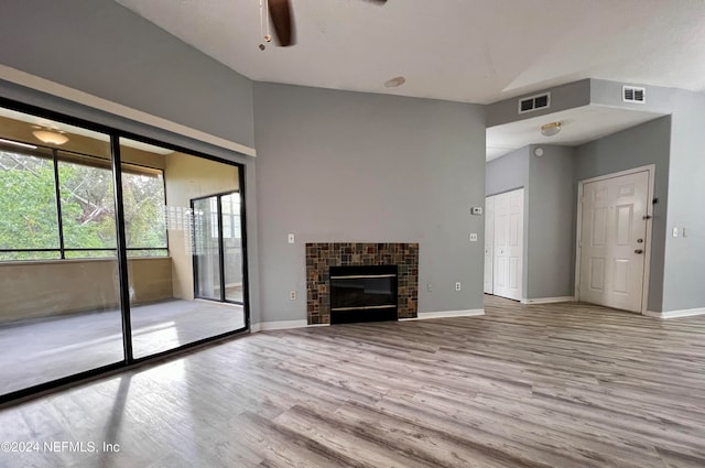 unfurnished living room with a tiled fireplace, ceiling fan, and light hardwood / wood-style flooring