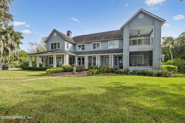 rear view of house featuring a yard, covered porch, and ceiling fan