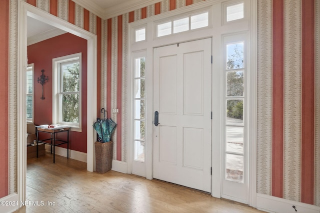 foyer entrance with light hardwood / wood-style flooring and ornamental molding