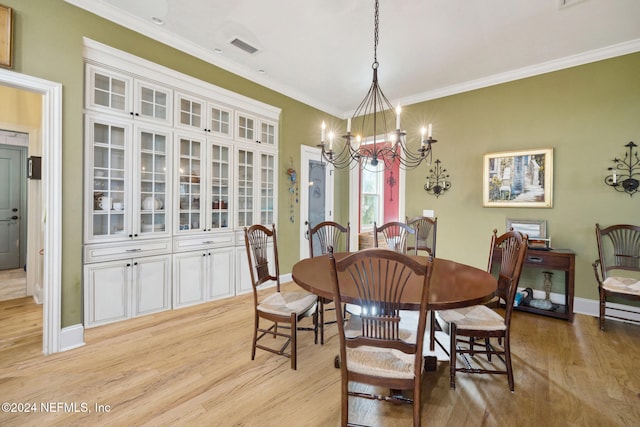 dining room with ornamental molding, light hardwood / wood-style floors, and an inviting chandelier