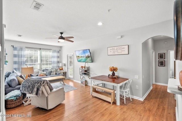 living room with a textured ceiling, light hardwood / wood-style floors, and ceiling fan