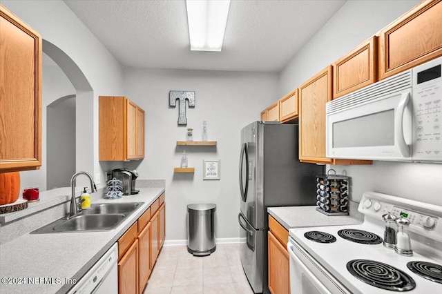 kitchen with light tile patterned floors, white appliances, a textured ceiling, and sink