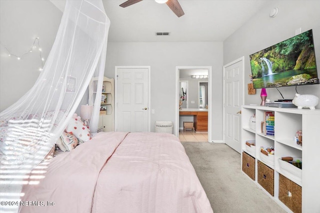 bedroom featuring light carpet, ensuite bathroom, and ceiling fan