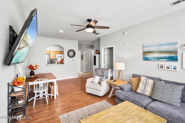 living room featuring ceiling fan, a textured ceiling, and hardwood / wood-style flooring