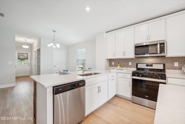 kitchen with kitchen peninsula, sink, stainless steel appliances, and light hardwood / wood-style floors