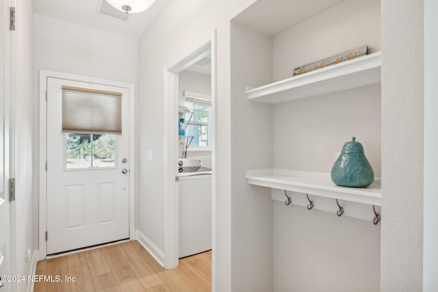 doorway with washer / clothes dryer, light hardwood / wood-style flooring, and a wealth of natural light