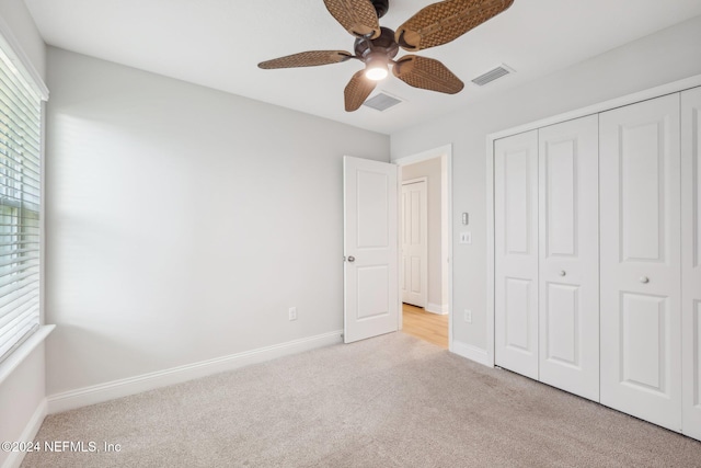 unfurnished bedroom with ceiling fan, a closet, and light carpet