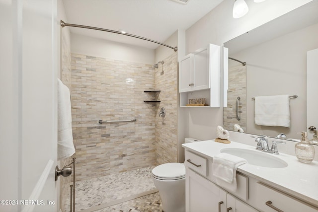 bathroom with tiled shower, vanity, and toilet