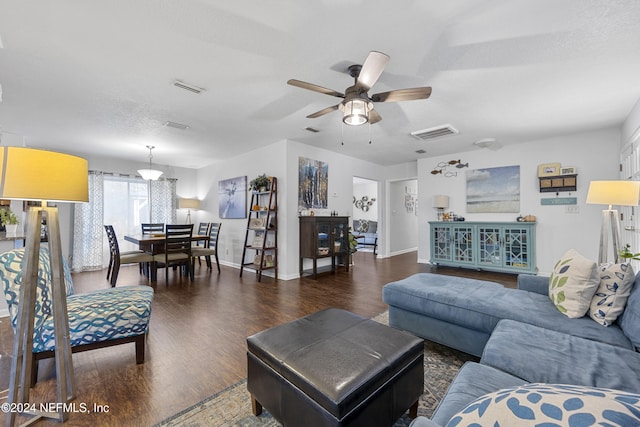 living room featuring dark hardwood / wood-style flooring, a textured ceiling, and ceiling fan