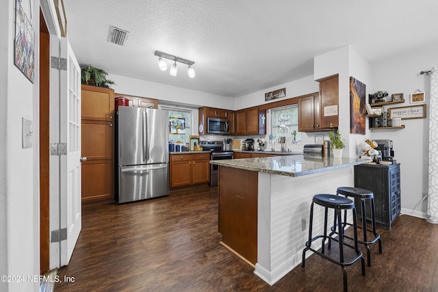 kitchen with stone counters, a healthy amount of sunlight, appliances with stainless steel finishes, and a textured ceiling