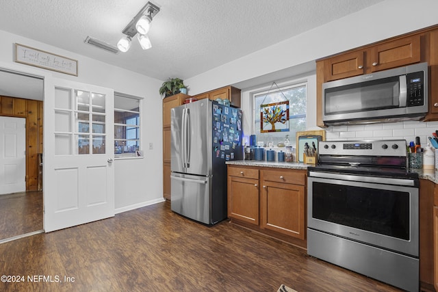 kitchen with decorative backsplash, appliances with stainless steel finishes, dark wood-type flooring, and a textured ceiling