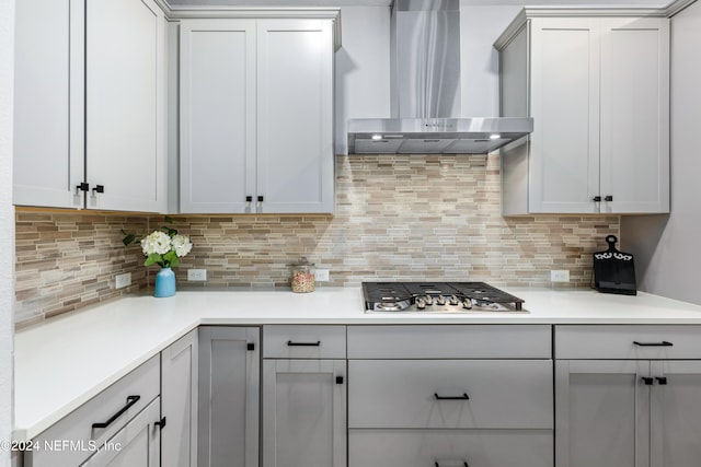 kitchen with stainless steel gas stovetop, wall chimney exhaust hood, and tasteful backsplash