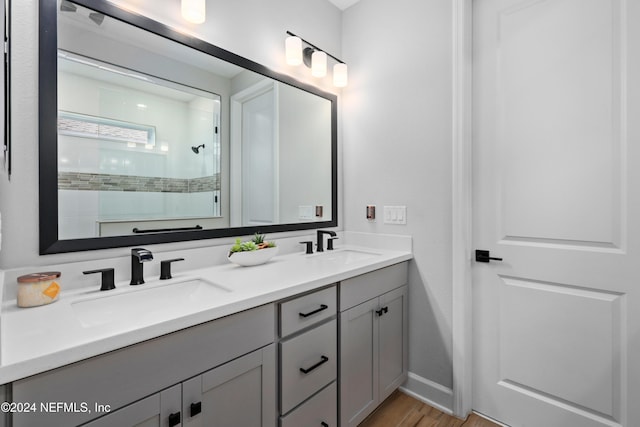 bathroom with hardwood / wood-style flooring, vanity, and tiled shower