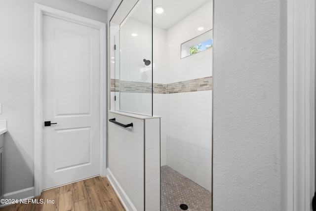 bathroom with hardwood / wood-style floors, vanity, and tiled shower