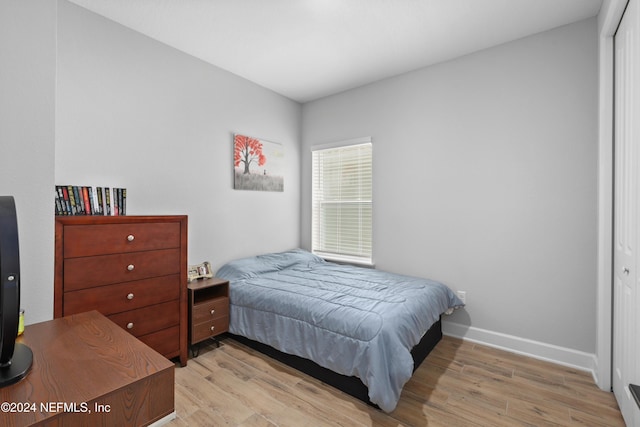 bedroom with light hardwood / wood-style floors and a closet