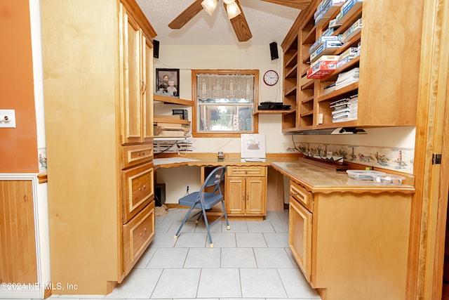 tiled home office featuring a textured ceiling, built in desk, and ceiling fan