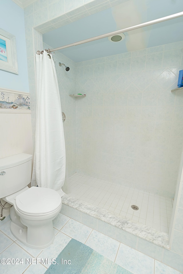 bathroom featuring toilet, a shower with shower curtain, and tile patterned floors