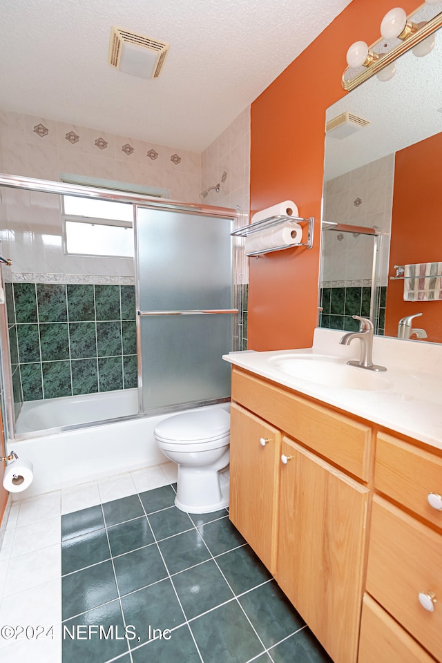 full bathroom with toilet, tile patterned floors, bath / shower combo with glass door, a textured ceiling, and vanity