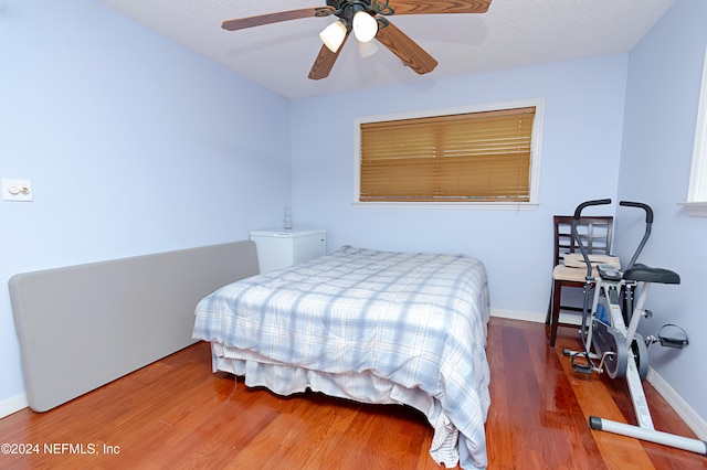 bedroom featuring hardwood / wood-style floors, ceiling fan, and a textured ceiling