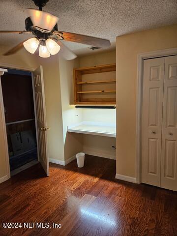 unfurnished bedroom with a textured ceiling, ceiling fan, dark hardwood / wood-style floors, and a closet