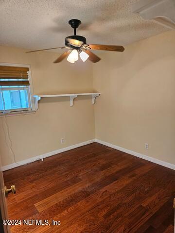 unfurnished room featuring dark wood-type flooring, a textured ceiling, and ceiling fan