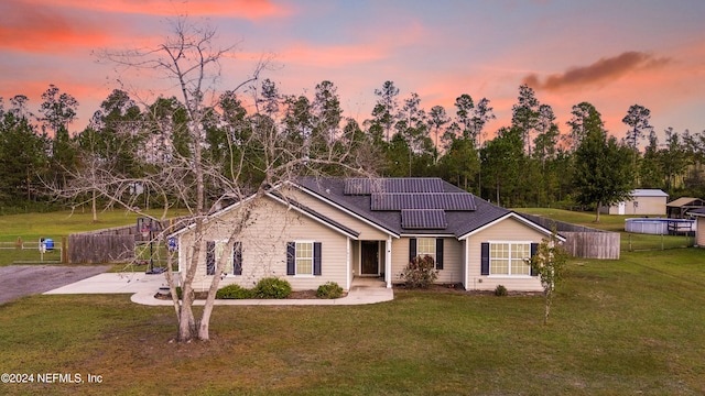 ranch-style home with solar panels, a lawn, and a patio