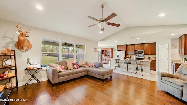 living room featuring hardwood / wood-style floors, vaulted ceiling, and ceiling fan