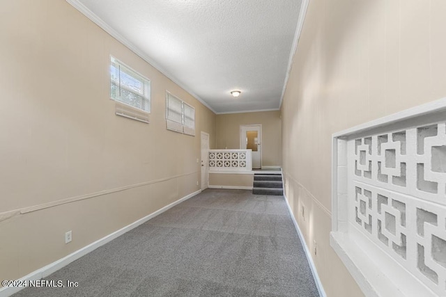 hall with a textured ceiling, carpet flooring, and ornamental molding