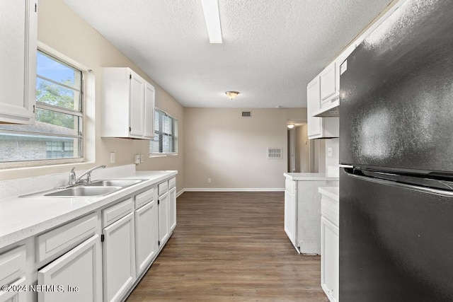 kitchen featuring white cabinetry, dark hardwood / wood-style flooring, sink, and black refrigerator