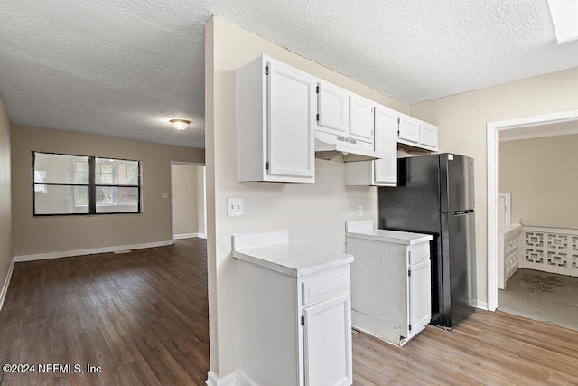 kitchen featuring refrigerator, a textured ceiling, light hardwood / wood-style floors, and white cabinets