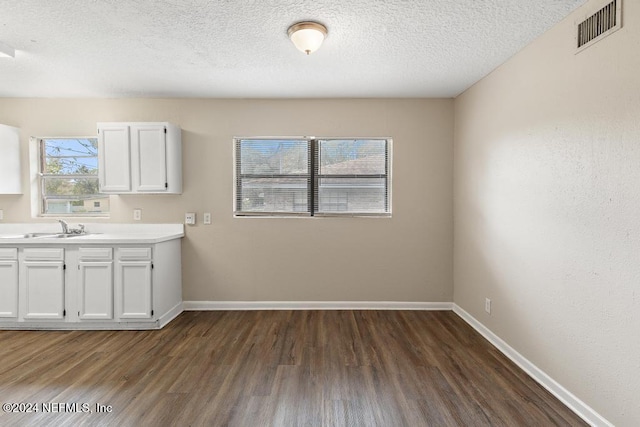 clothes washing area with dark hardwood / wood-style flooring, sink, and a textured ceiling