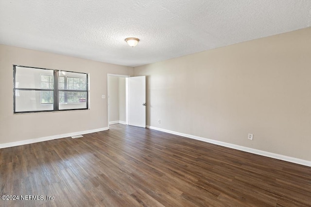 spare room with a textured ceiling and dark hardwood / wood-style flooring