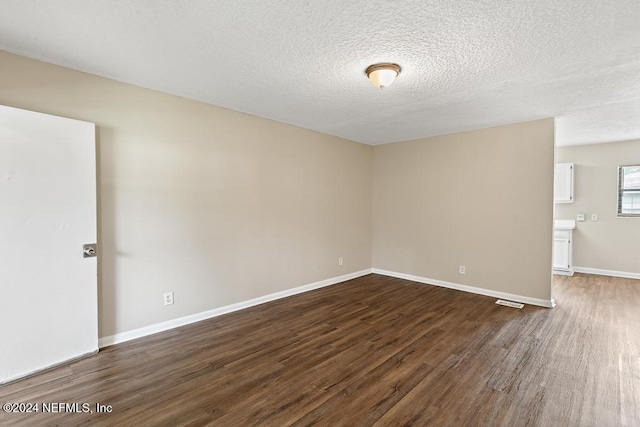 spare room with dark wood-type flooring and a textured ceiling