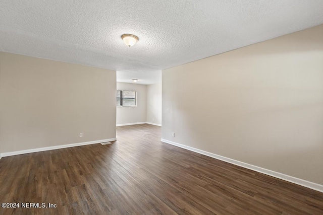 empty room featuring dark hardwood / wood-style floors and a textured ceiling