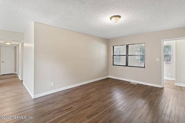 spare room featuring dark wood-type flooring and a textured ceiling