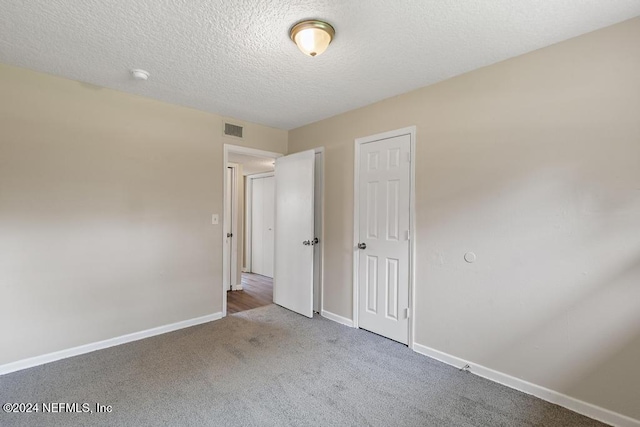 unfurnished bedroom featuring a textured ceiling, carpet flooring, and a closet