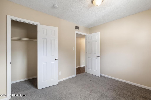 unfurnished bedroom with light colored carpet, a textured ceiling, and a closet