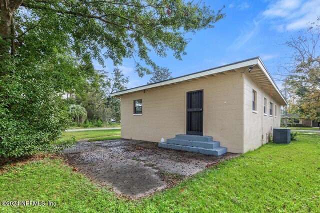 rear view of property with cooling unit and a yard