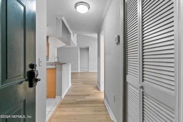 hall featuring light wood-type flooring, sink, and crown molding