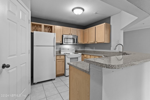 kitchen with a peninsula, white appliances, dark countertops, and a sink