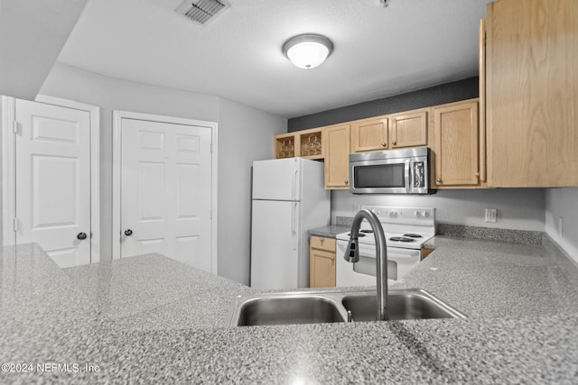 kitchen with a textured ceiling, light brown cabinetry, white appliances, and sink